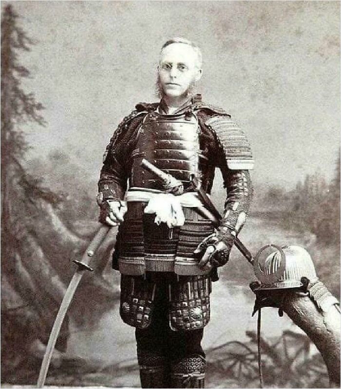 A man in historical samurai armor, holding a sword, with a forest backdrop.
