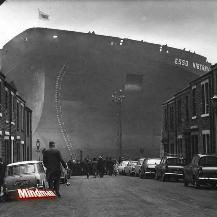 Massive ship towering over a street filled with people and cars, illustrating megalophobia with its scarily large size.