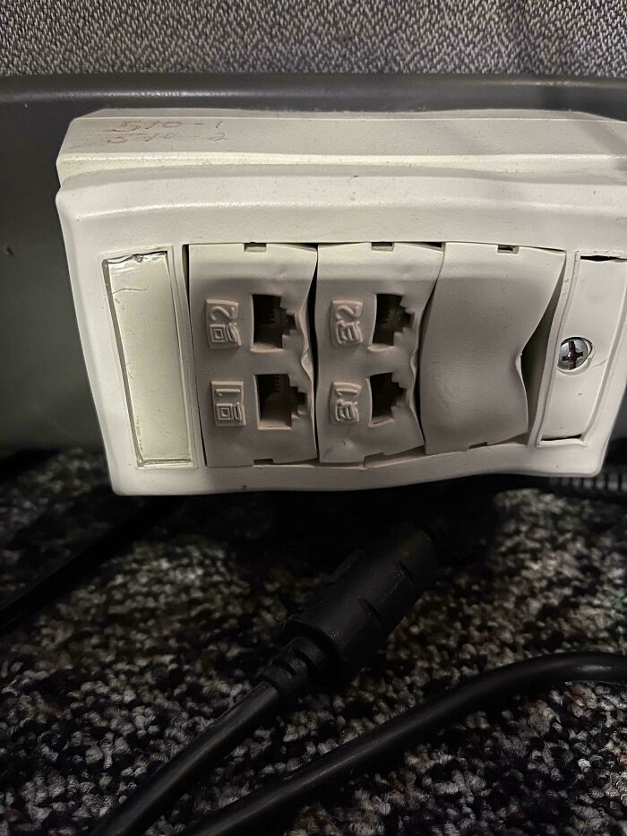 Close-up of damaged tech support work wall connectors with melted and warped plastic around network ports.