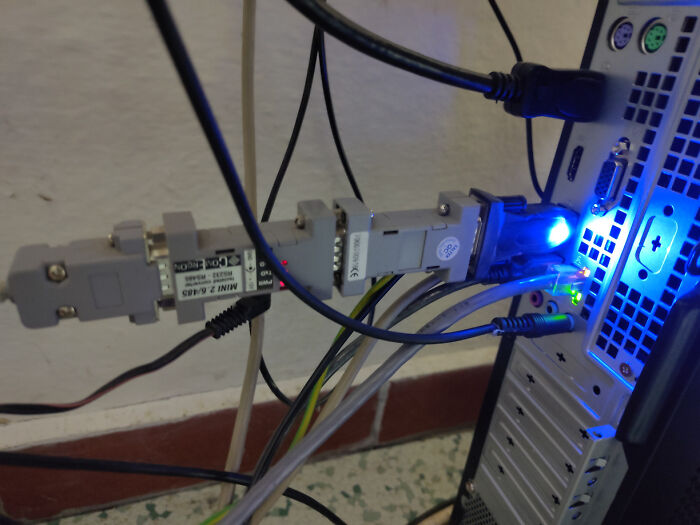 Close-up of messy cables and connectors plugged into the back of a desktop computer, illustrating tech support challenges.