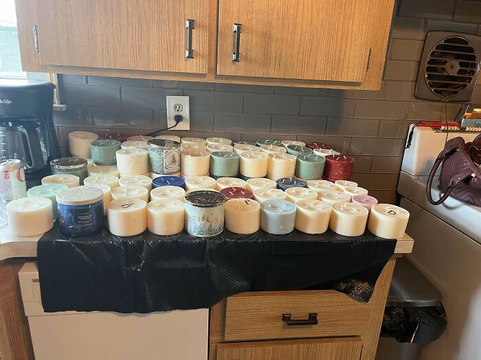 A variety of candles discovered during dumpster diving displayed on a kitchen counter.