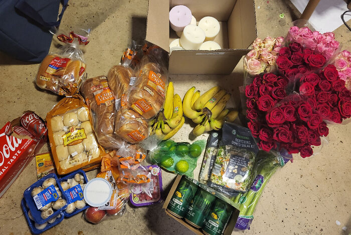 Dumpster diving haul with bread, bananas, flowers, and groceries on the floor.