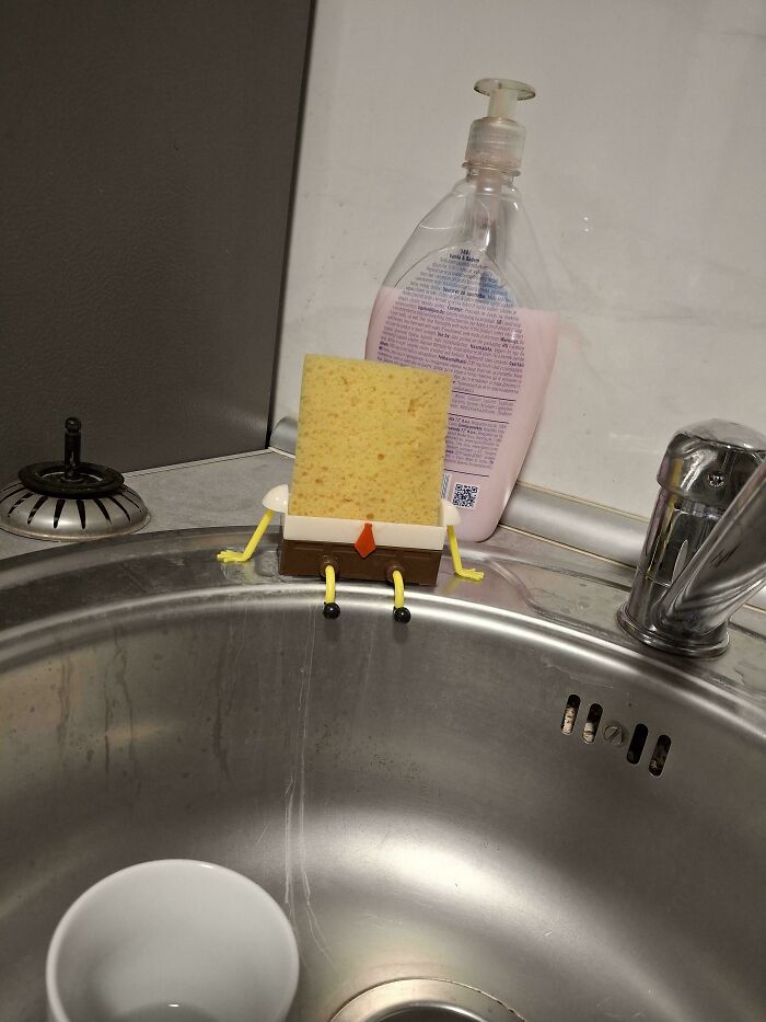 Sponge shaped like a cartoon character sits on a sink, offering mildly interesting amusement in a kitchen setting.