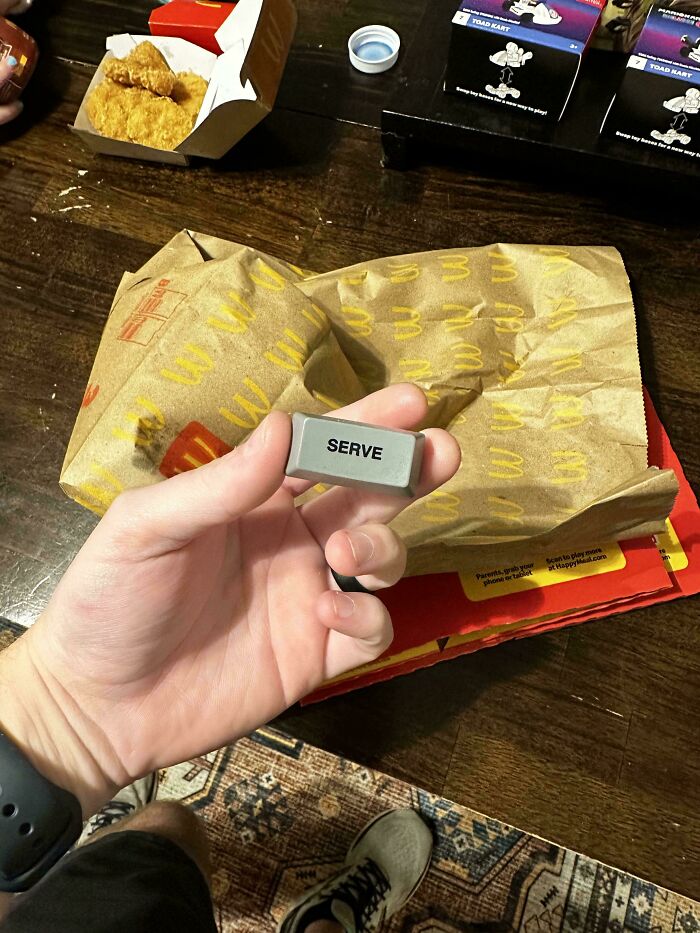 A hand holding a key labeled "SERVE" over a fast food meal, mildly interesting.