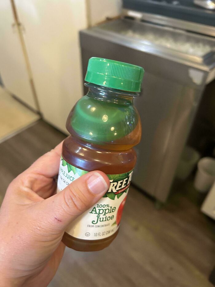 Person holding a bottle of apple juice with a green cap, mildly interesting detail.