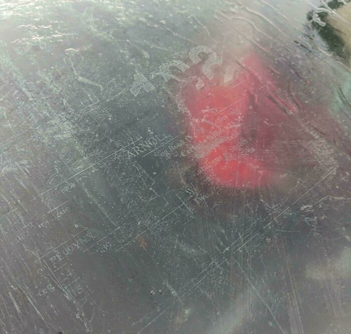 Weathered car hood with an outline of a map and faint red paint, showcasing mildly interesting details.