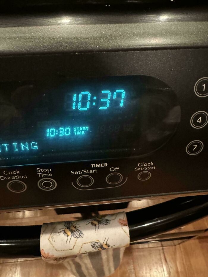 Digital oven clock displaying 10:37, next to a printed bees towel, offering mildly interesting details.