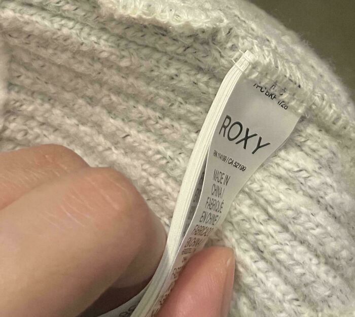 Hand holding clothing tag with brand name "Roxy," offering mildly interesting detail about the item's origin.