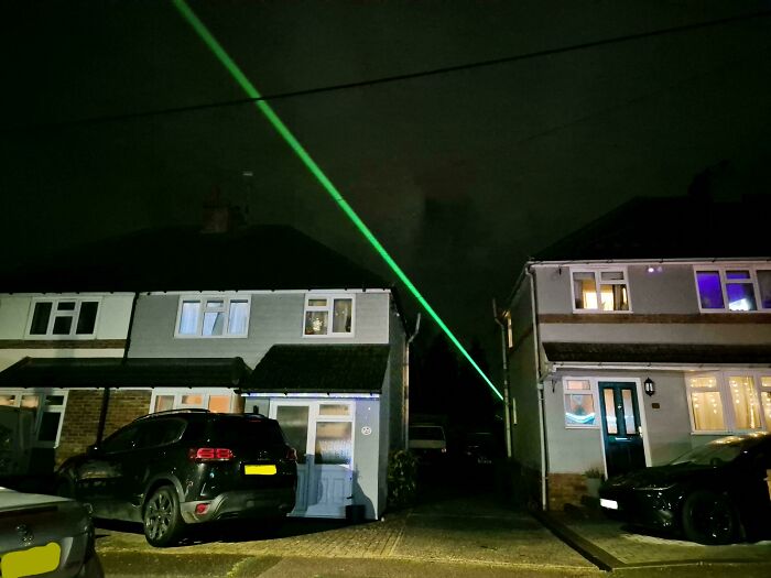 Night scene with a green laser beam crossing over suburban houses, creating a mildly interesting effect.