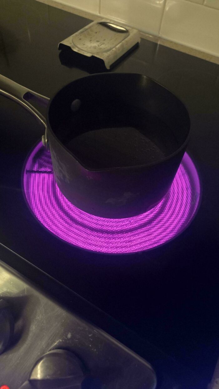 Mildly interesting image of a saucepan on an electric stove with a glowing purple burner.