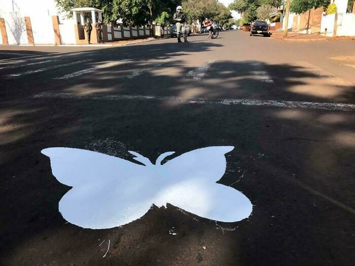 White butterfly stencil on a street, creating mildly interesting visual amid urban surroundings.