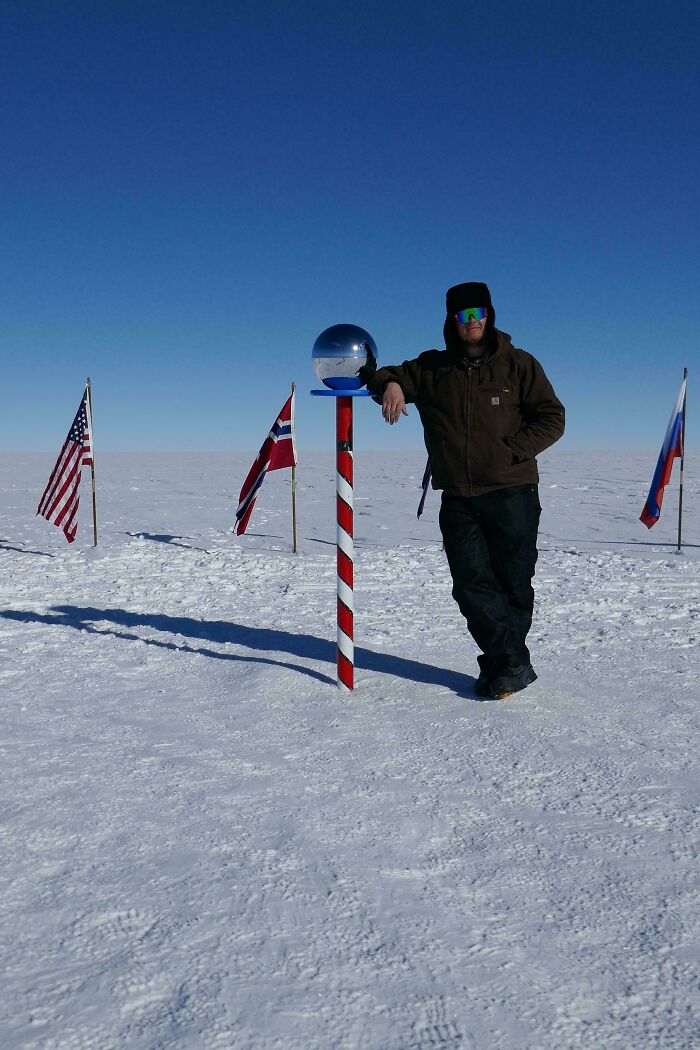 Person standing at icy pole with flags; an example of mildly interesting sights for temperate amusement.