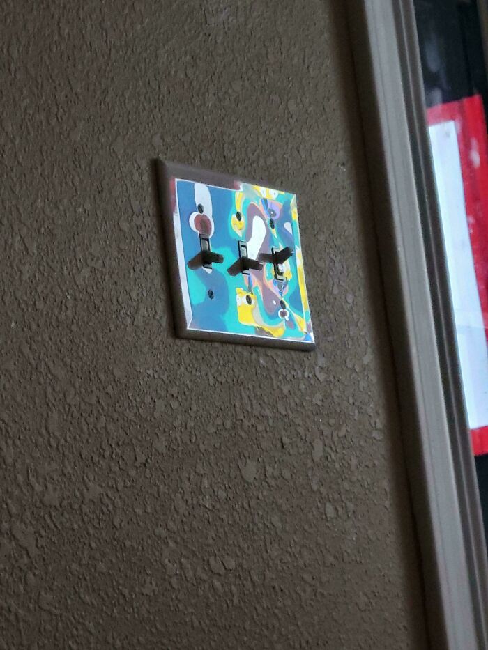 Colorful light switch plate with abstract patterns in a mildly interesting setting.
