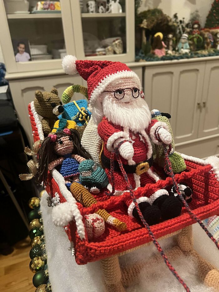 Crochet Santa Claus with gifts and toys on a sleigh, showcasing detailed crochet craftsmanship by enthusiasts.