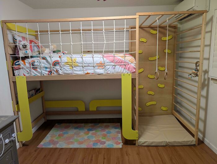 Loft bed with climbing wall and rope, showcasing a dad's rewarding creativity in making a fun play area for kids.