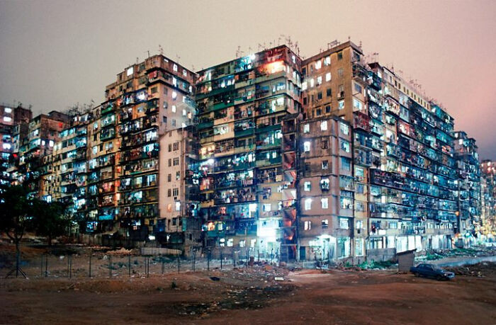 Dilapidated urban housing complex at night, illustrating urban hell conditions with lit windows and crowded structures.