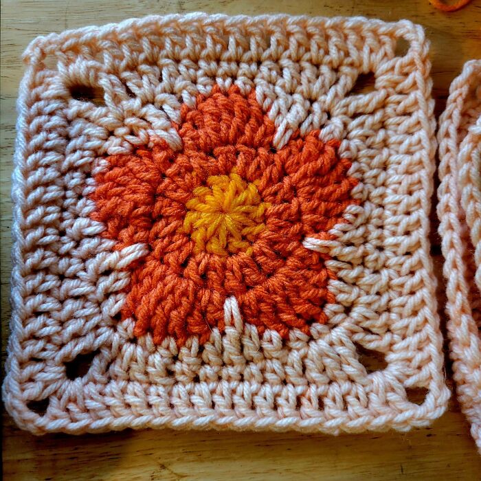 Crochet square with an orange and yellow flower pattern, showcasing detailed stitches for crochet enthusiasts to admire.