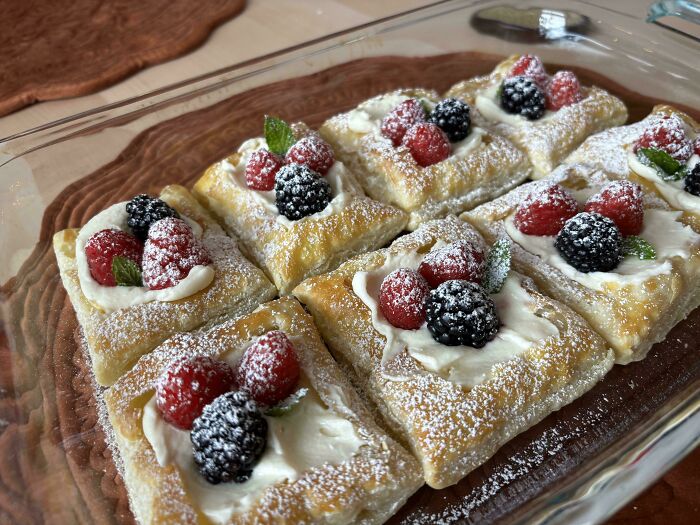 Gourmet pastries topped with cream, raspberries, and blackberries, showcasing bakers' next-level culinary skills.