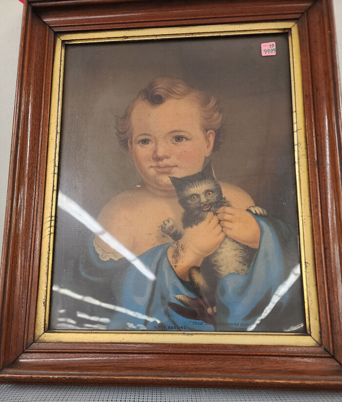 Framed vintage portrait of a child holding a cat, discovered while thrifting.