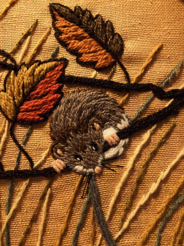Detailed embroidery design of a small mouse surrounded by autumn leaves on fabric, showcasing beautiful stitching techniques.