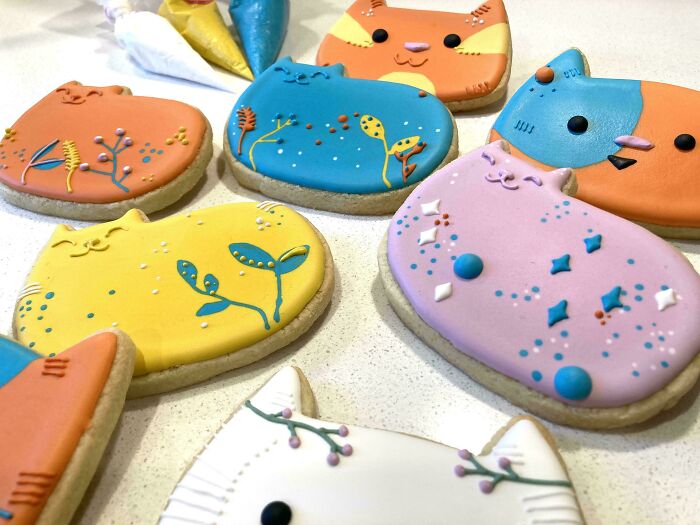 Colorful cat-shaped cookies with intricate icing designs, showcasing bakers' creativity and culinary ingenuity.