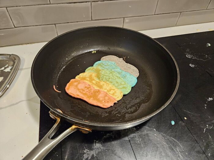 Rainbow-colored pancake in a frying pan, showcasing a dad's creativity in cooking for his children.