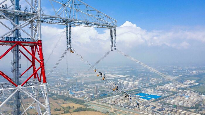 High-voltage power lines and brilliant infrastructure connecting industrial facilities with clear blue sky background.