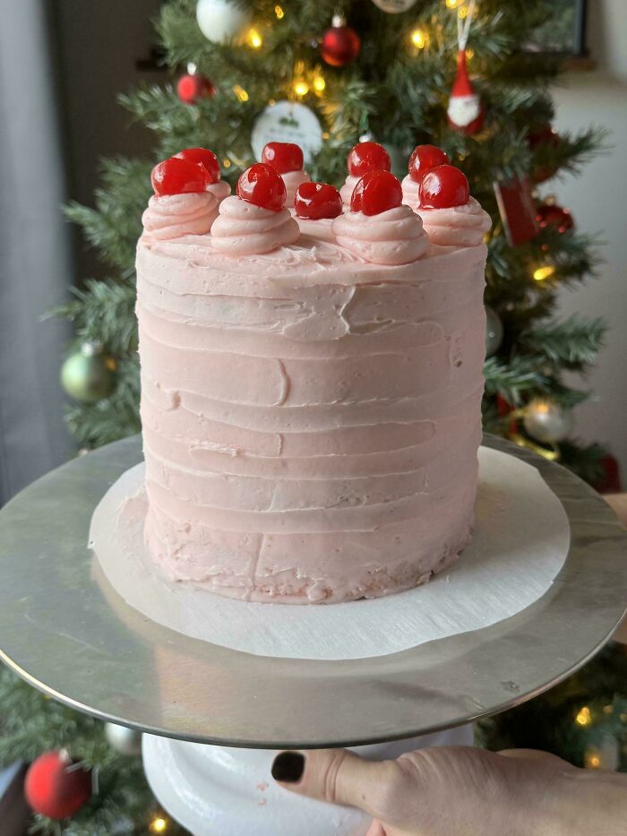 Pink cake with cherries on top, decorated for Christmas, showcasing advanced baking skills.