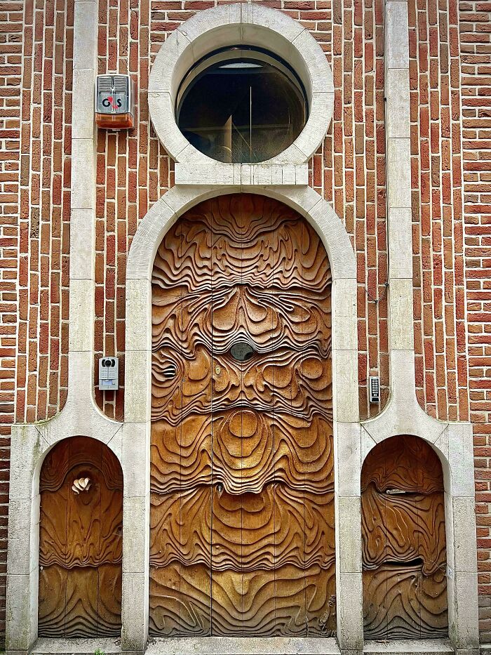 Intricately carved wooden door with abstract topographic design set in brick wall, showcasing impressive architectural feats.