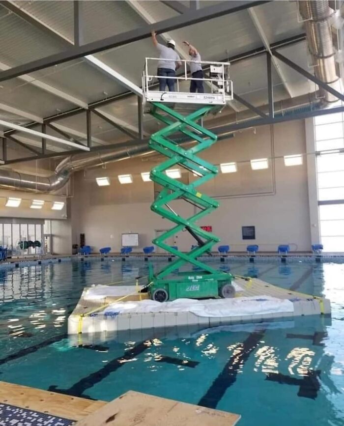 Workers On A Scissor Lift Floating In A Swimming Pool