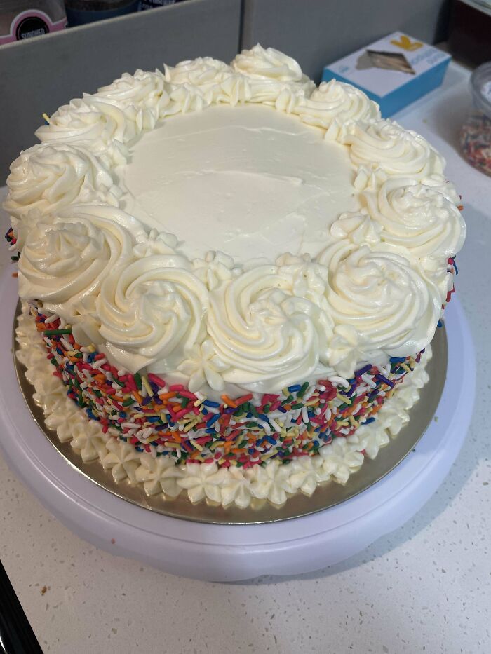 A decorated cake with white frosting and colorful sprinkles, showcasing bakers' culinary creativity and skill.