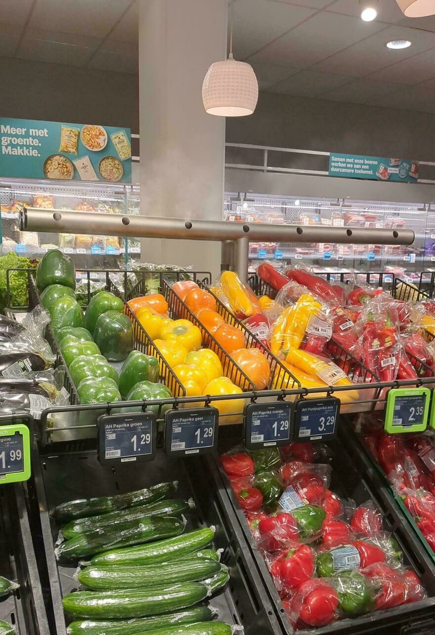 Colorful bell peppers wrapped in unnecessary packaging on a supermarket shelf, highlighting wasteful practices.