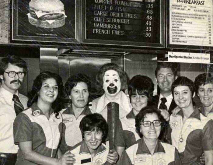 Group of fast-food restaurant employees with a clown mascot in a vintage setting, illustrating fascinating historical pics.