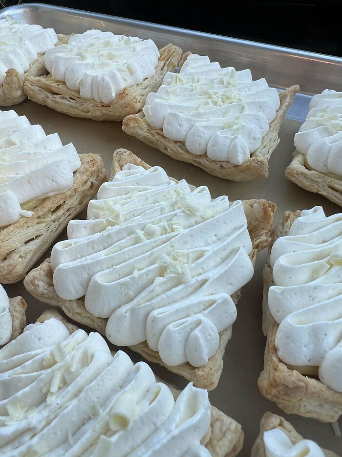 Puff pastries topped with swirls of whipped cream, showcasing bakers' culinary prowess.