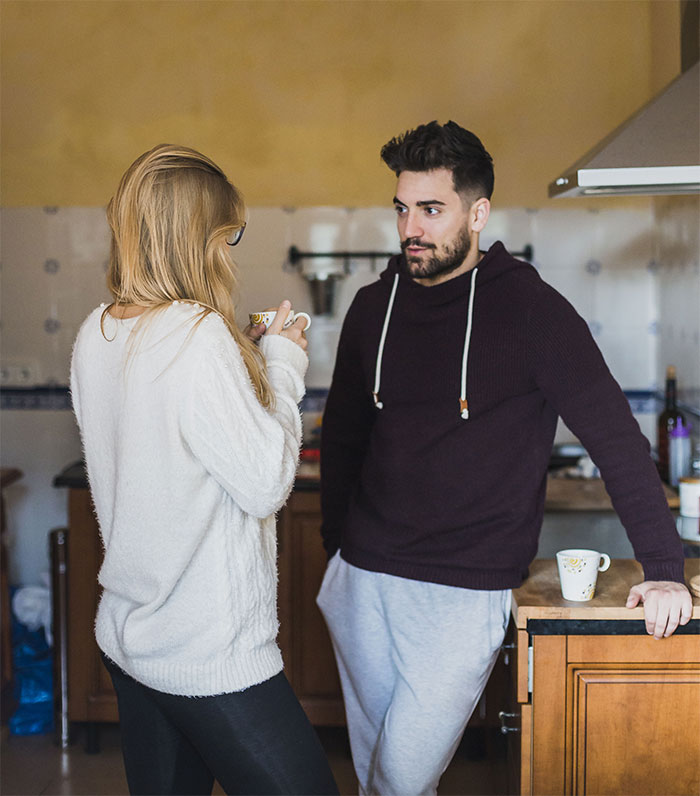 Couple discussing wedding dress choice in a cozy kitchen setting.