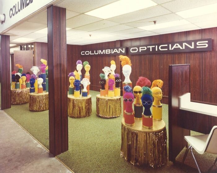 1973 optician display with colorful mannequin heads showcasing eyewear in a retro store setting.
