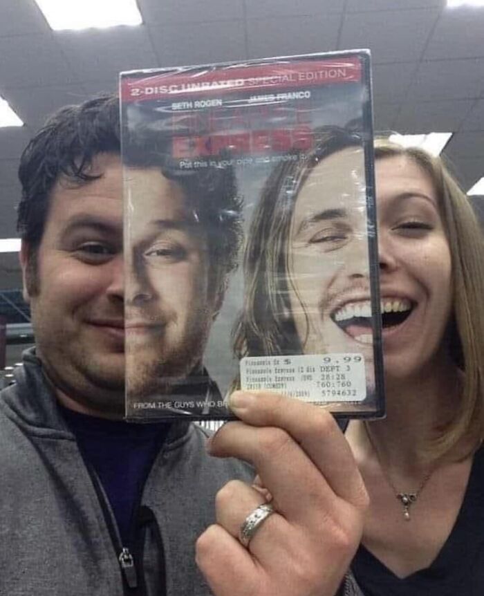 Two people holding a DVD cover aligned with their faces, creating a funny, album cover-like illusion.