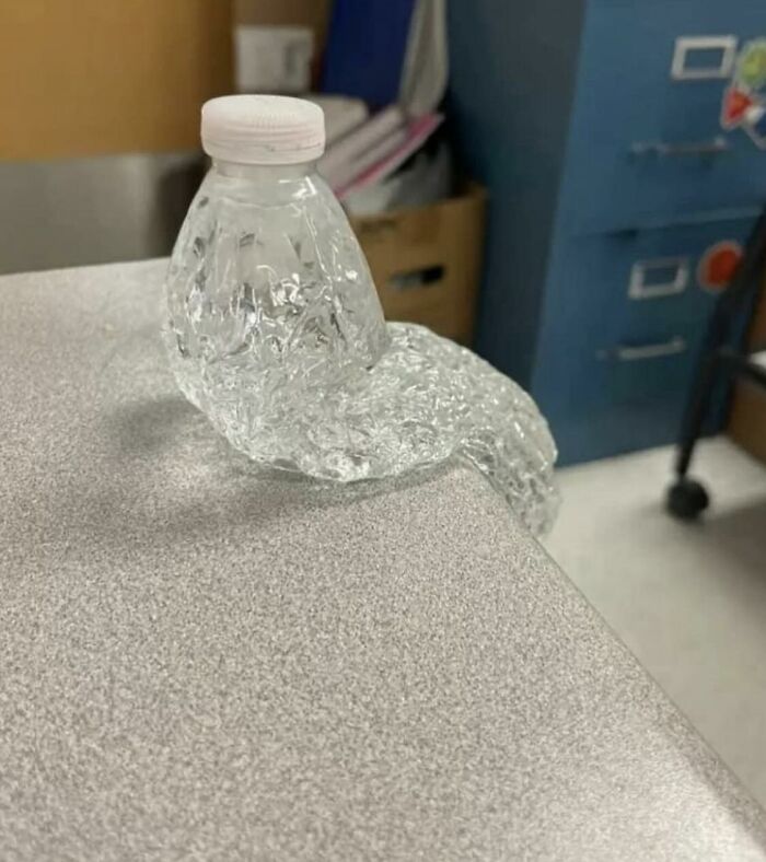 Weird photo of a distorted, partially melted plastic bottle on a countertop, resembling an abstract sculpture.