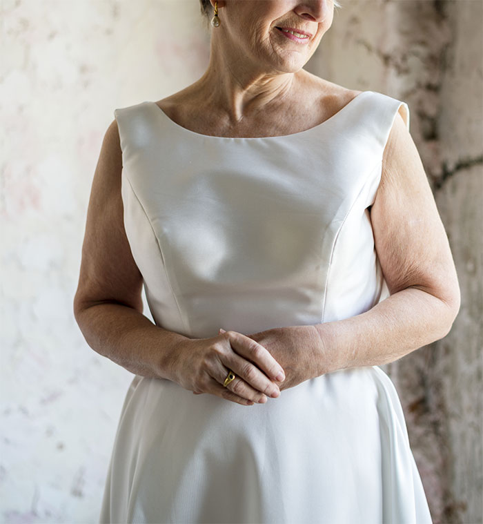 Woman in a white dress standing indoors, showing the concept of a bride's attire and family dynamics.