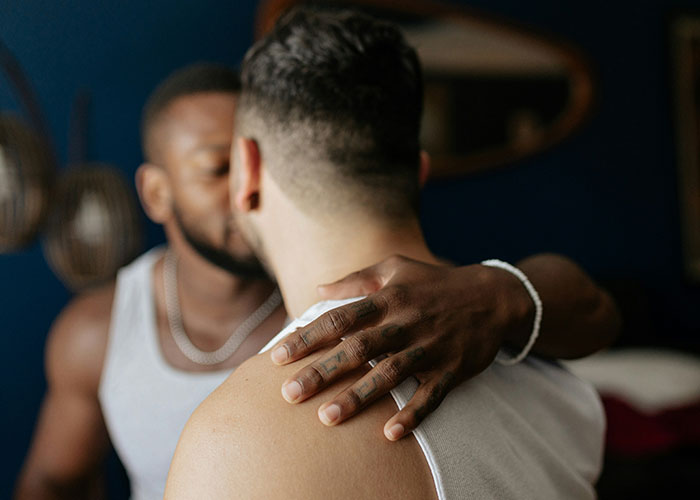 Two people in an intimate moment, one with a hand on the other's shoulder, symbolizing secret revelations.