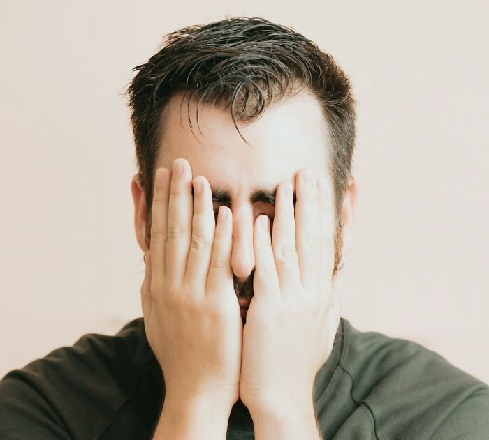 Man covering his face with hands, expressing frustration and really messed up moments.