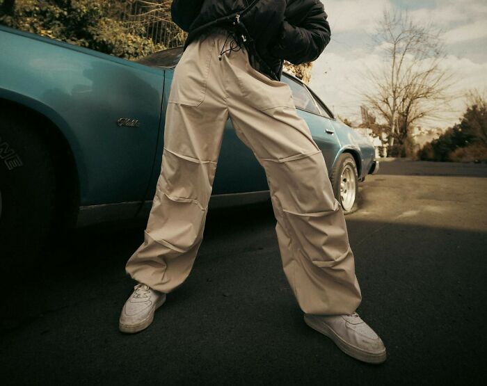 Baggy cargo pants, a trend from 2024 people might avoid, styled with sneakers next to a vintage car.