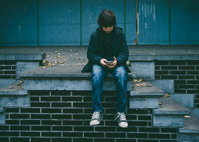 Child sitting on steps with a phone, surrounded by autumn leaves, representing wild 911 calls in dispatcher memories.