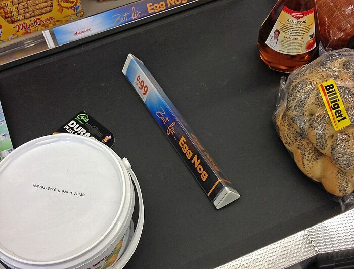 Supermarket checkout with unusual egg nog sign, bread, and other items.