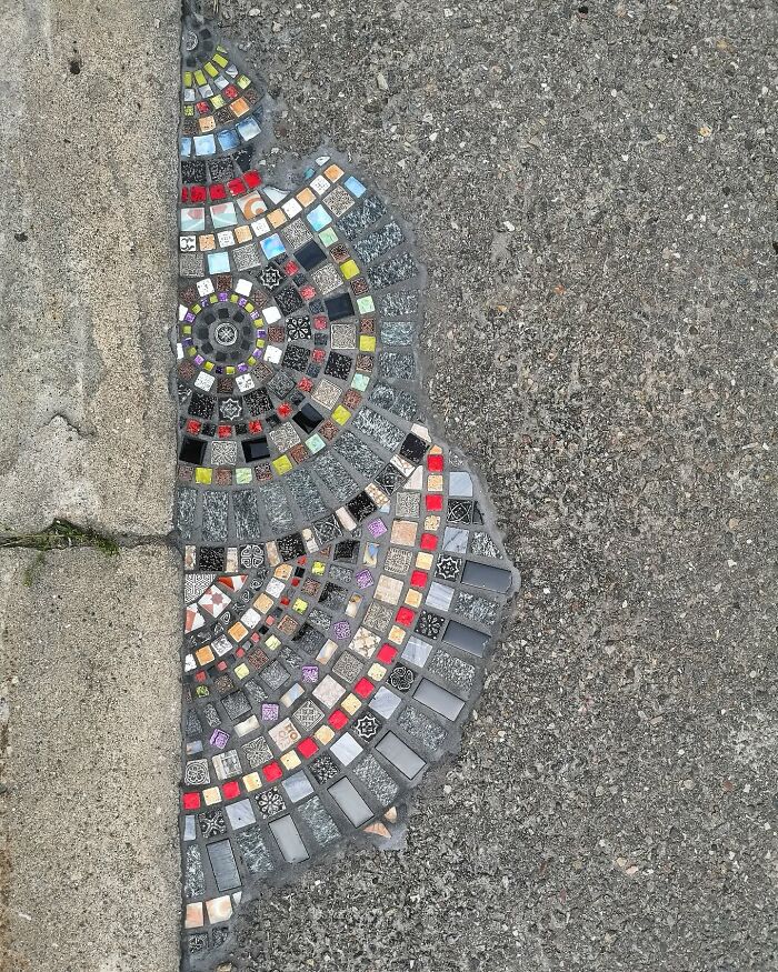 Vibrant mosaic art mending a c*****d sidewalk with colorful tiles and patterns.