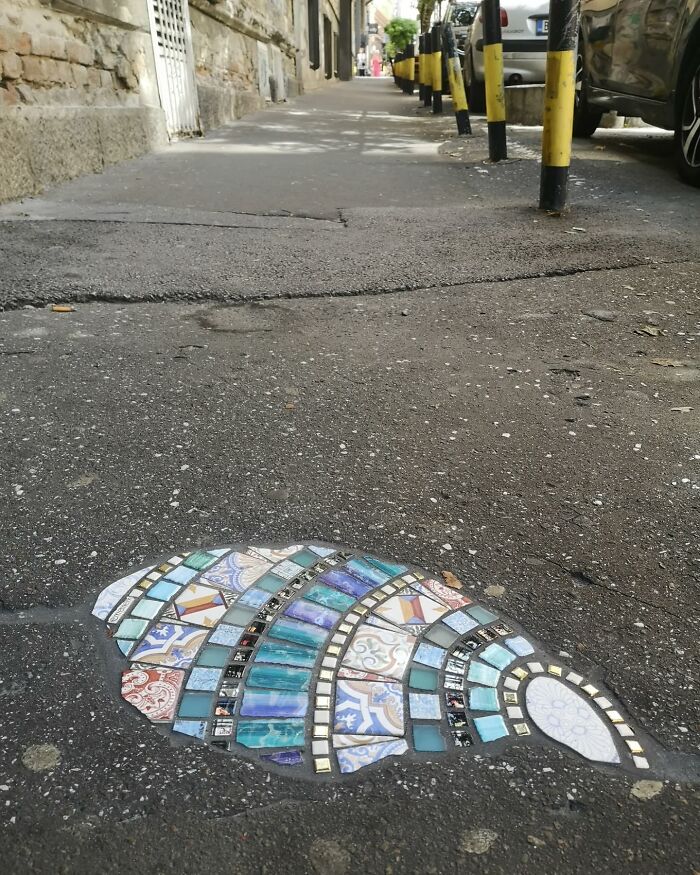 Vibrant mosaics repair a c*****d sidewalk, showcasing colorful tiles and artistic restoration.