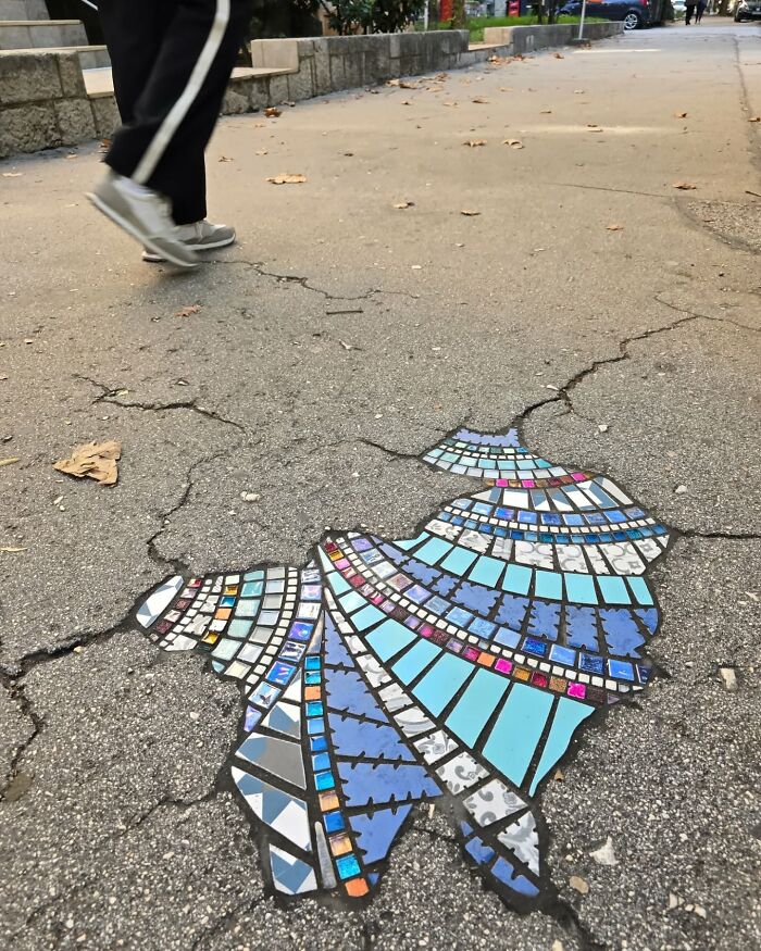 Vibrant mosaic art mends c*****d sidewalk, adding color and creativity to the urban environment.