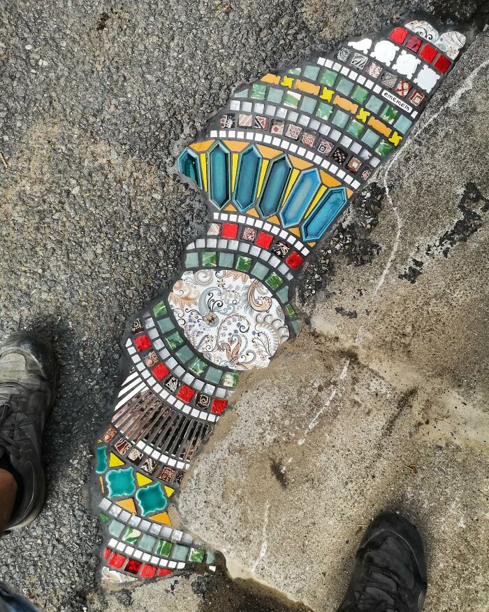 Vibrant mosaic art fills a c*****d sidewalk, showcasing colorful tiles and intricate designs.