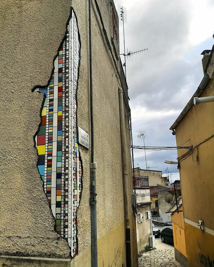 Vibrant mosaic art patching a c*****d building wall, adding color and creativity to the urban landscape.