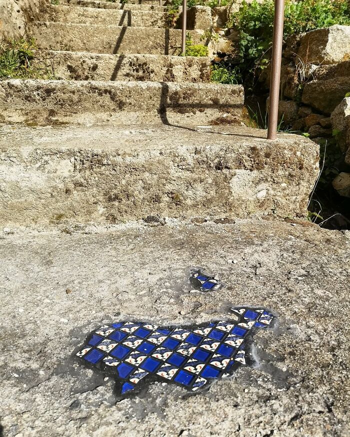Vibrant mosaic art mends c*****d sidewalk, blending blue tiles with stone surface.